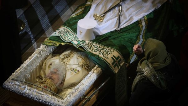 An orthodox faitfhul bends on the casket casket of late Serbian patriarch Irinej during his funeral service at Belgrade's cathedral, on November 21, 2020. Patriarch Irinej, the head of the Serbian Orthodox Church, died of coronavirus on November 20, 2020, three weeks after his unofficial second-in-command also succumbed to Covid-19, the church said. OLIVER BUNIC / AFP