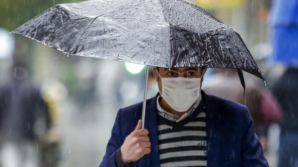 A pedestrian, mask-clad due to the COVID-19 coronavirus pandemic, walks with an umbrella past closed shops along a street in Iran's capital Tehran on November 21, 2020, as the Iranian government announced new pandemic-countering measures. STR / AFP 