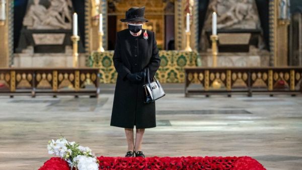 Britain's Queen Elizabeth II looks on as her Equerry, Lieutenant Colonel Nana Kofi Twumasi-Ankrah (L) places a bouquet of flowers at the grave of the Unknown Warrior to mark the centenary of the burial of the Unknown Warrior ahead of Remembrance Sunday at Westminster Abbey in London on November 4, 2020. (AFP)