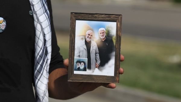 A supporter of the Iran-backed Hashed al-Shaabi (Popular Mobilisation) paramilitary forces carries a frame with pictures of slain Iranian commander Qassem Soleimani (L), Iraqi paramilitary commander Abu Mahdi Al-Muhandis (R), the late founder of the Islamic Republic Ayatollah Ruhollah Khomeini and its Supreme Leader Ayatollah Ali Khamenei, in Baghdad's Karrada neighbourhood on October 17, 2020. AHMAD AL-RUBAYE / AFP