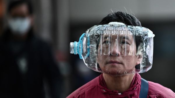A woman wears a plastic water bottle with a cutout to cover her face, as she walks on a footbridge in Hong Kong on January 31, 2020, as a preventative measure following a virus outbreak which began in the Chinese city of Wuhan. The World Health Organization, which initially downplayed the severity of a disease that has now killed 170 nationwide, warned all governments to be "on alert" as it weighed whether to declare a global health emergency. Anthony WALLACE / AFP