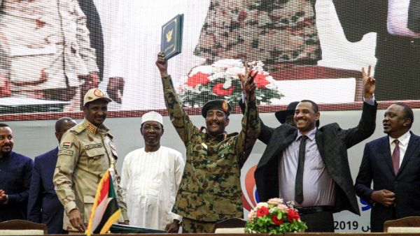 In this file photo taken on August 17, 2019, Sudan's protest leader Ahmad Rabie (2nd-R), flashes the victory gesture alongside General Abdel Fattah al-Burhan (C), the chief of Sudan's ruling Transitional Military Council (TMC), during a ceremony where they signed a "constitutional declaration" that paves the way for a transition to civilian rule, in the capital Khartoum, accompanied by General Mohamed Hamdan Daglo "Hemeti" (2nd-L), TMC deputy chief and commander of the Rapid Support Forces (RSF) paramilitar