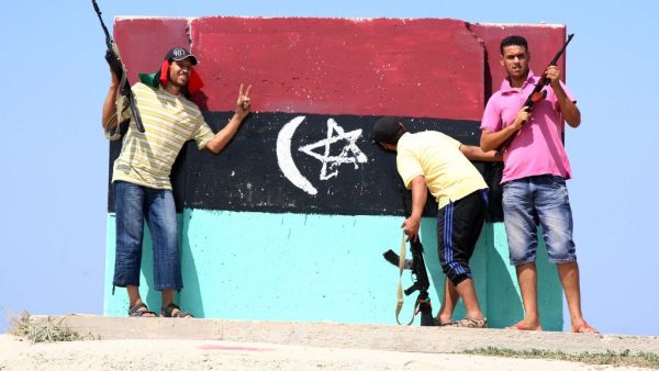In this file photo taken in Tripoli on August 22, 2011, Libyan rebels stand in front of a freshly painted wall with the flag of Libya's monarchy, which ruled from independence in 1951 until overthrown by Moamer Kadhafi in 1969. Mahmud TURKIA / AFP