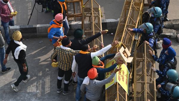 Farmers offer bananas and jaggery to the Indian security personnel at a road block stopping farmers from marching to New Delhi to protest against the central government's recent agricultural reforms at the Delhi-Uttar Pradesh state border in Ghazipur on December 1, 2020. Sajjad HUSSAIN / AFP
