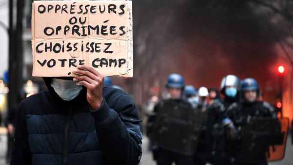 A protester holds a sign reading "Oppressors or oppressed, choose your side" in front of riot mobile gendarmes during a demonstration for 'social rights' and against the 'global security' draft law, which Article 24 would criminalise the publication of images of on-duty police officers with the intent of harming their 'physical or psychological integrity', in Paris, on December 5, 2020. Anne-Christine POUJOULAT / AFP