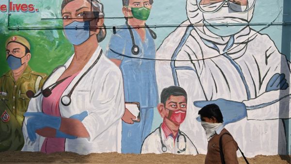 A man walks past a mural depicting Covid-19 coronavirus frontline workers in New Delhi on December 9, 2020. Sajjad HUSSAIN / AFP