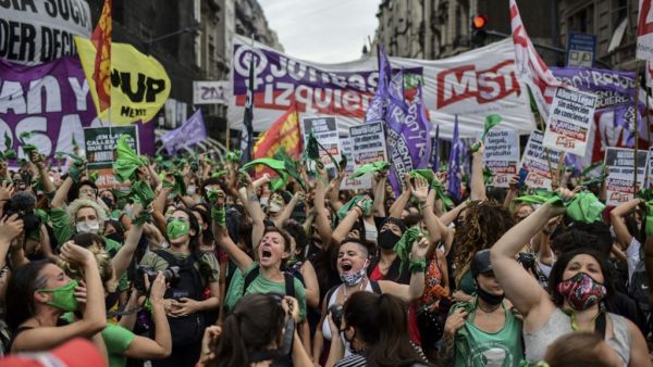 Demonstrators celebrate with green headscarves - the symbol of abortion rights activists - outside the Argentine Congress in Buenos Aires on December 11, 2020, after legislators passed a bill to legalize abortion. RONALDO SCHEMIDT / AFP