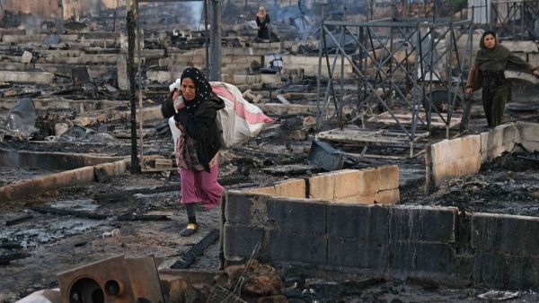Syrian refugees salvage belongings from the wreckage of their shelters at a camp set on fire overnight in the northern Lebanese town of Bhanine on December 27, 2020, following a fight between members of the camp and a local Lebanese family. The United Nations refugee agency, UNHCR, confirmed a large fire had broken out in a camp in the Miniyeh region and said some injured had been taken to hospital, but did not provide an exact number. Ibrahim CHALHOUB / AFP