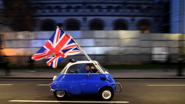 In this file photo taken on January 31, 2020 A man waves Union flags from a BMW Isetta as he drives past Brexit supporters gathering in Parliament Square, in central London on January 31, 2020, the day that the UK formally leaves the European Union. Severing a truculent partnership stretching back five decades, Britain finally went its own way late Thursday four-and-a-half years after its shock referendum verdict in favour of divorcing the EU. Brexit became reality as Big Ben struck 11:00 pm (2300 GMT) in c