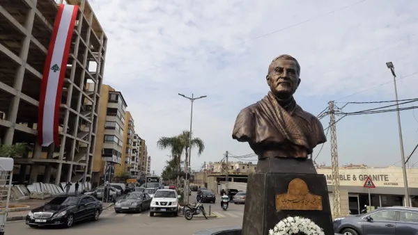 A photo taken on January 5, 2021 shows a Lebanese flag hanging on a building under construction behind the newly unveiled statue of Iran's most revered military commander, Qasem Soleimani, in the predominantly-Shiite Muslim Beirut southern suburb of Ghobeiry. Soleimani -- whom the US blamed for attacks on its interests in Iraq and elsewhere -- was killed in a US drone strike at Baghdad airport on January 3 last year, ratcheting up tensions between decades-old arch foes the United States and Iran. JOSEPH EID