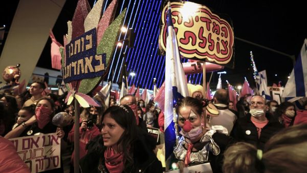Israelis lift placards and flags as they take part in a demonstration against Prime Minister Benjamin Netanyahu at the entrance to the city in Jerusalem, amid the coronavirus pandemic crisis, on January 9, 2021. MENAHEM KAHANA / AFP