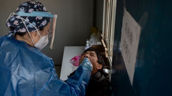 A woman (R) gets a nucleic acid test at a testing booth outside the Red Cross hospital in Wuhan on January 11, 2021, as the city marks the first anniversary of when China confirmed its first death from the COVID-19 coronavirus. NICOLAS ASFOURI / AFP