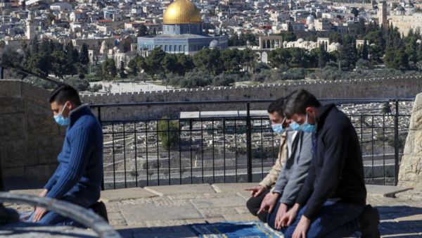 Mask-clad Palestinians, unable to reach the Al-Aqsa mosque compound amidst strengthened restriction due to the coronavirus, perform Friday prayers at the Mount of Olives overlooking the compound in the Old City of Jerusalem, on January 22, 2021. AHMAD GHARABLI / AFP
