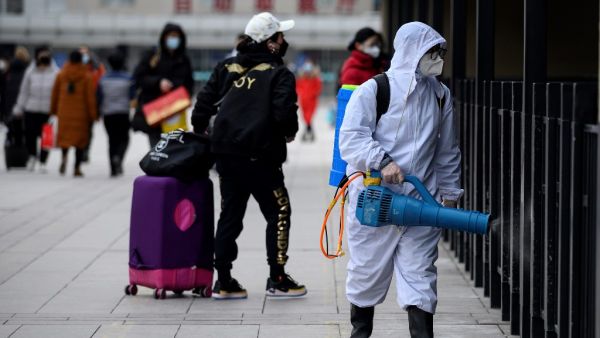 A worker disinfects the departure area of the Beijing railway station on January 27, 2021. NOEL CELIS / AFP