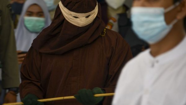 A member of the Sharia police (L) prepares to cane a man (R) accused of having gay sex in Banda Aceh on January 28, 2021. Aceh is the only region in the world's biggest Muslim-majority nation that imposes Islamic law -- known as Sharia -- with those found guilty of breaches often publicly whipped with a rattan cane. CHAIDEER MAHYUDDIN / AFP
