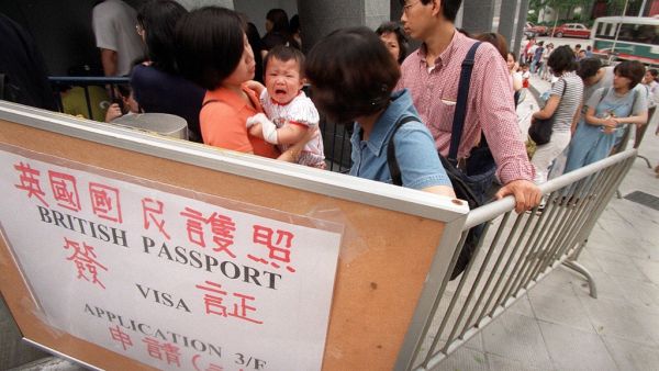 This file photo taken on June 20, 1997 shows people queueing outside the British Council in Hong Kong in hopes of applying for a British National (Overseas) passport, or "BNO", before the handover to China on June 30, 1997 over anxiety about the city's future. A new visa scheme offering millions of Hong Kongers a pathway to British citizenship will go live later on January 31, 2021 as the city's former colonial master opens its doors to those wanting to escape China's crackdown on dissent. STEPHEN SHAVER / 