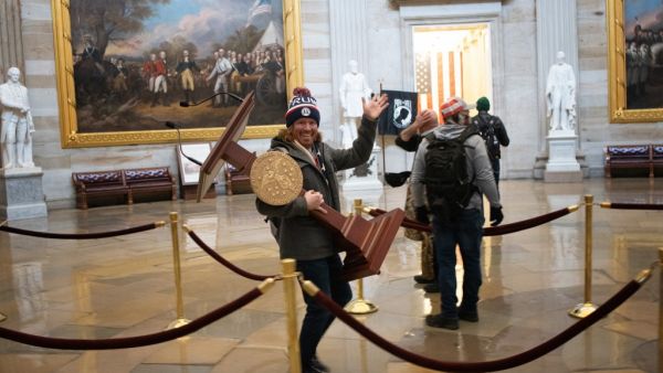 A pro-Trump protester carries the lectern of U.S. Speaker of the House Nancy Pelosi through the Roturnda of the U.S. Capitol Building after a pro-Trump mob stormed the building on January 06, 2021 in Washington, DC. (AFP/File)