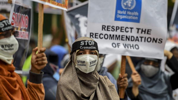 Protesters hold placards during a demonstration against the government policy of forced cremations of Muslims who died of the Covid-19 coronavirus, outside a cemetery in Colombo. (AFP)