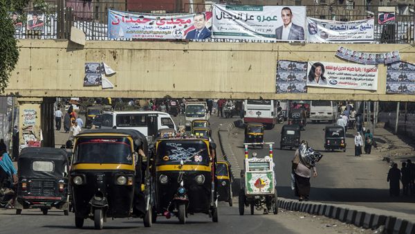 Egyptians drive rickshaws also known as "tuk-tuks" along a road displaying banners of parliamentary election candidates in the Imbaba district of the Egyptian capital, Cairo, Oct. 15, 2015. Photo by KHALED DESOUKI/AFP/Getty Images. 
