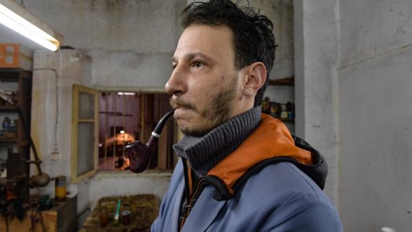 Anis Bouchnak tries a briar wood pipe that he made at his workshop in the northwestern Tunisian coastal town of Tabarka, on January 28, 2021. Bouchnak, 37, who in 2011 took over the family business started by his grandfather, is the only craftsman in Tunisia, and one of the few in the region, to continue to make pipes by hand. FETHI BELAID / AFP