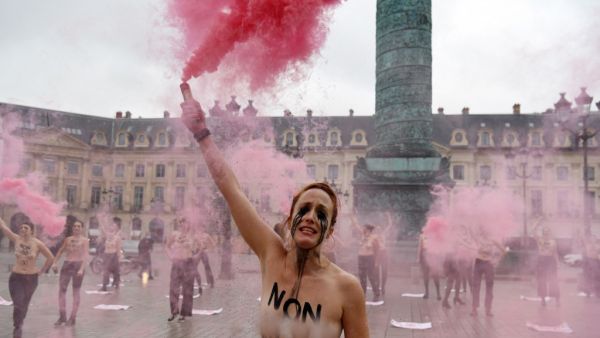 A Femen activist, with "not guilty" written on the chest, lights flares during a protest against sexism in the French judicial system at the Vendôme square in Paris on February 6, 2021. Alain JOCARD / AFP