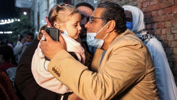 Mahmoud Hussein (R), an Egyptian national and senior journalist for Qatar-based Al Jazeera Arabic, kisses a child upon his arrival at his family home in the Giza village of Zawyet Abu Musallam, about 30 kilometres south of Egypt's capital Cairo on February 6, 2021 upon his release from detention. Egypt has freed the journalist for Qatar's Al Jazeera after four years in jail without trial following the end last month of a rift between the two Arab states. Mahmoud Hussein, an Egyptian national who had been im