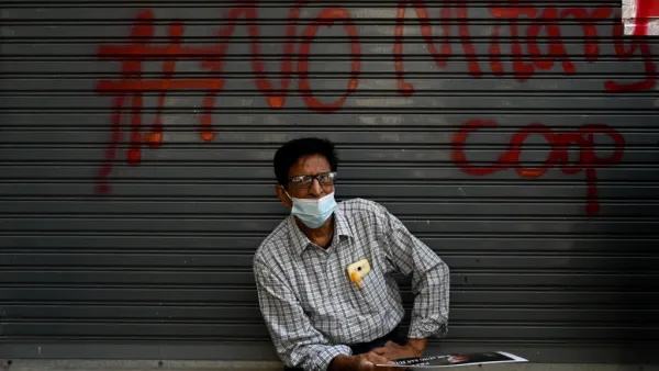 A protester sits in front a graffiti during a demonstration against the military coup in Yangon on February 9, 2021. Ye Aung THU / AFP