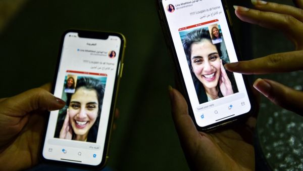 This picture taken February 10, 2021 in Saudi Arabia's capital Riyadh shows a woman viewing a tweet posted by the sister of Saudi activist Loujain al-Hathloul, Lina, showing a screenshot of them having a video call following Hathloul's release after nearly three years in detention. Saudi authorities on February 10 released the prominent women's rights activist, her family said, as the kingdom comes under renewed US pressure over its human rights record. Hathloul, 31, was arrested in May 2018 with about a do