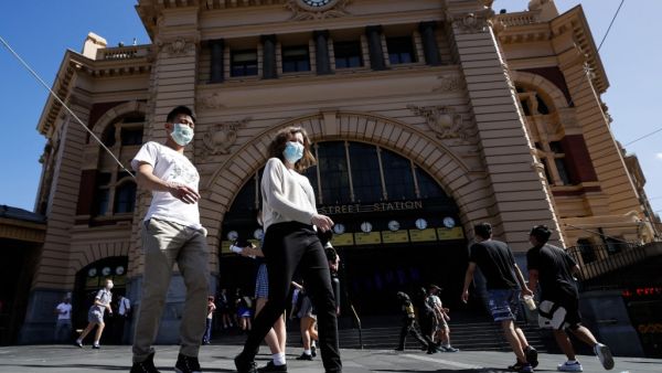 People cross a street in Melbourne on February 12, 2021, after authorities ordered a five-day state-wide lockdown starting at midnight local time to stamp out a new coronavirus outbreak. Con Chronis / AFP