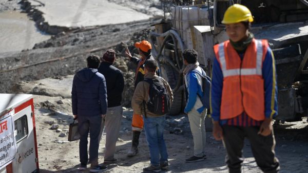 Defence research and development organisation (DRDO) scientists talk with an emergency and rescue official (in orange cap) after arriving near Tapovan tunnel, where dozens are still feared to be trapped, during rescue operations in Tapovan of Chamoli district on February 12, 2021 following a flash flood thought to have been caused when a glacier burst on February 7. Virender SINGH NEGI / AFP