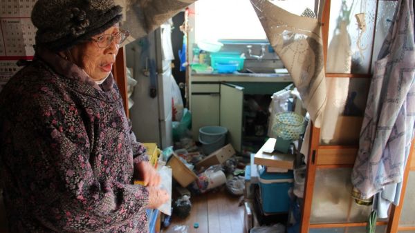 Japanese woman Taeko Naito stands next to her scattered kitchen at her home in Soma, Fukushima prefecture on February 14, 2021, after a 7.3-magnitude earthquake struck off Japan's east coast late on February 13. STR / JIJI PRESS / AFP