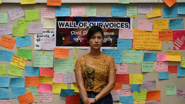 A woman stands in front of a wall with protest messages during a demonstration against the military coup in Yangon on February 18, 2021. Sai Aung Main / AFP