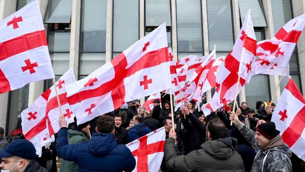 Georgian opposition supporters wave national flags reacting on the announcement of Prime Minister Giorgi Gakharia's resignation in front of the United National Movement (UNM) headquarters in Tbilisi on February 18, 2021. Vano Shlamov / AFP