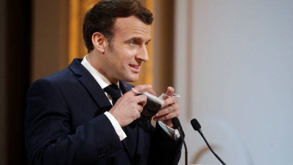 French President Emmanuel Macron removes his protective face mask as he attends the 2021 Munich Security Conference held by video link at the Elysee Palace in Paris on February 19, 2021 amidst the coronavirus disease (Covid-19) outbreak. BENOIT TESSIER / POOL / AFP