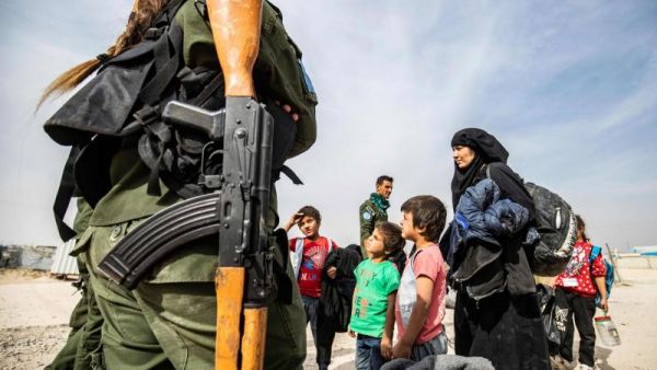 A Kurdish fighter looks on as Syrian women and children, suspected of being related to Islamic State (ISIS) group fighters, gather at the Kurdish-run al-Hol camp, on October 28. (AFP)