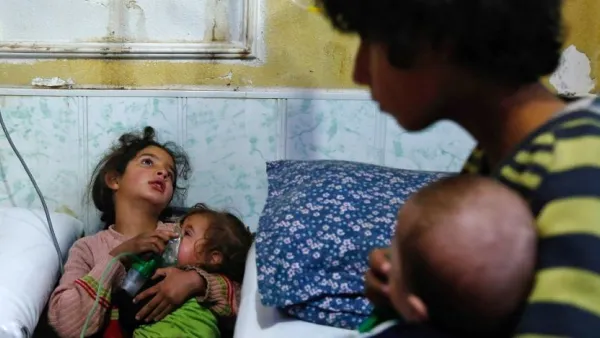 A Syrian girl holds an oxygen mask over the face of an infant at a make-shift hospital after a gas attack on Douma in the eastern Ghouta region on the outskirts of Damascus on January 22, 2018. (AFP)