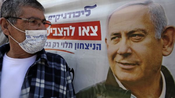 An Israeli wearing a mask with the Likud party logo