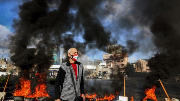 A man wearing a cross necklace and clad in mask depicting the Lebanese flag 