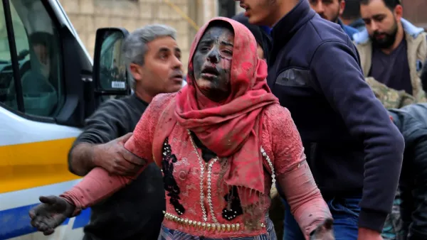 Syrian men help a wounded woman covered in dust 