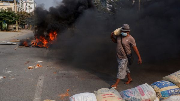 A man carries a sandbag to erect a makeshift barricade, as security forces staged a crackdown on demonstrations by protesters against the military coup, in Mandalay on March 22, 2021. STR / AFP New sanctions imposed on Myanmar military over latest coup
