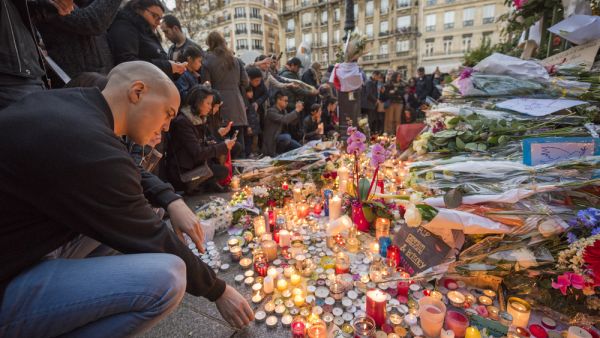 A man lights a candle in front of the theater Le Bataclan in tribute to victims of the  terrorist attack in Paris