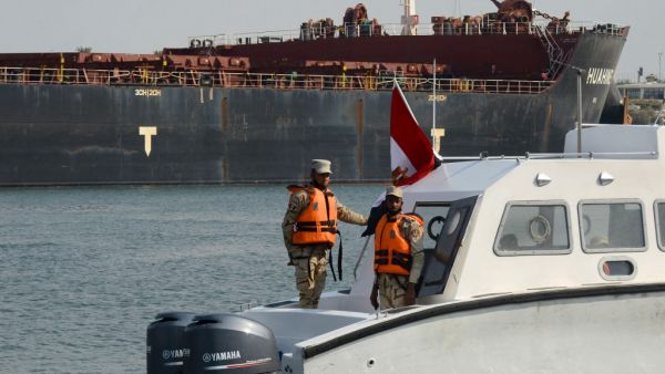 Egyptian coast guards patrol as a ship navigates the Suez Canal on March 30, 2021, a day after a cargo vessel was dislodged from its banks. Egyptian authorities have presented the freeing of the megaship, which was stuck for nearly a week and caused a 425- ship tailback to the north and south, as a major vindication of the country's engineering and salvage capabilities. Tarek WAJEH / AFP