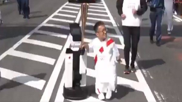 A robot helping to carry the Olympic torch (Image: Tokyo Olympics Twitter) 