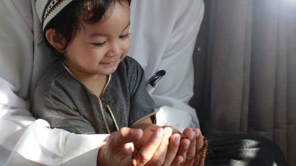 Asian Muslim Man teaching his little son to pray to God 
