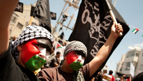 Faces painted with the Palestinian flag, boys march in Ramallah on Nakba Day