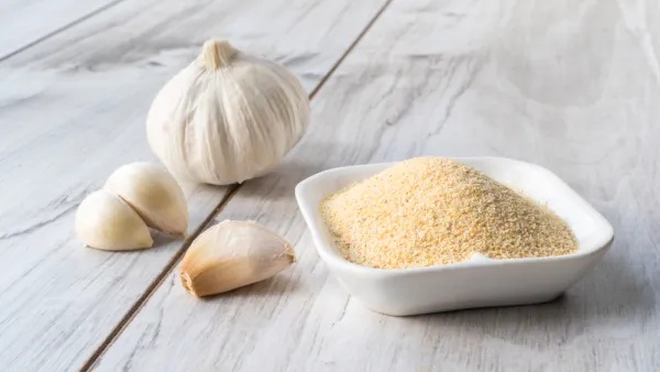 Bowl with granulated dried garlic on wooden table