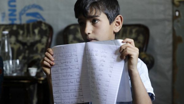Eleven-year-old Syrian refugee Mohammad shows his Arabic writing notebook inside his family's tent at a refugee camp in the area of Tebrol in Lebanon's eastern Bekaa valley 