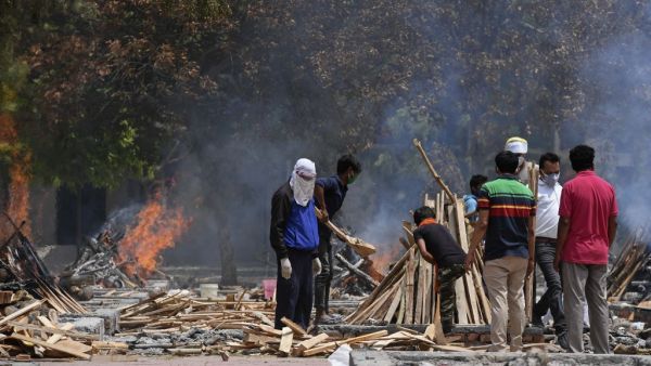 Relatives stand near burning pyres of people who died of the Covid-19 