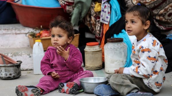 Palestinan children eat as families took shelter at a United Nations (UN) school in Rafah in the southern Gaza Strip on May 17, 2021. Israeli air strikes hammered the Hamas-controlled territory after a week of violence which has killed more than 200 people, the large majority Palestinian, despite international calls for de-escalation