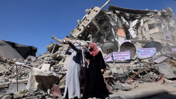 Palestinian women pose for a 'selfie' picture in front of a demolished building in the Al-Remal commercial district in Gaza City, recently targeted by Israeli air strikes, on May 23, 2021. Gazans started piecing back their lives after a devastating conflict with Israel that killed more than 200 people and made thousands homeless in the impoverished Palestinian enclave, days after an Egypt-brokered ceasefire ended deadly Israeli air strikes and rocket fire out of it towards Israel